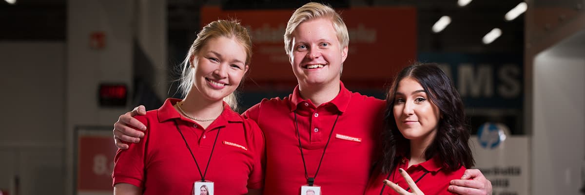 Verkkokauppa.comin hymyileviä työntekijöitä punaisissa paidoissaan