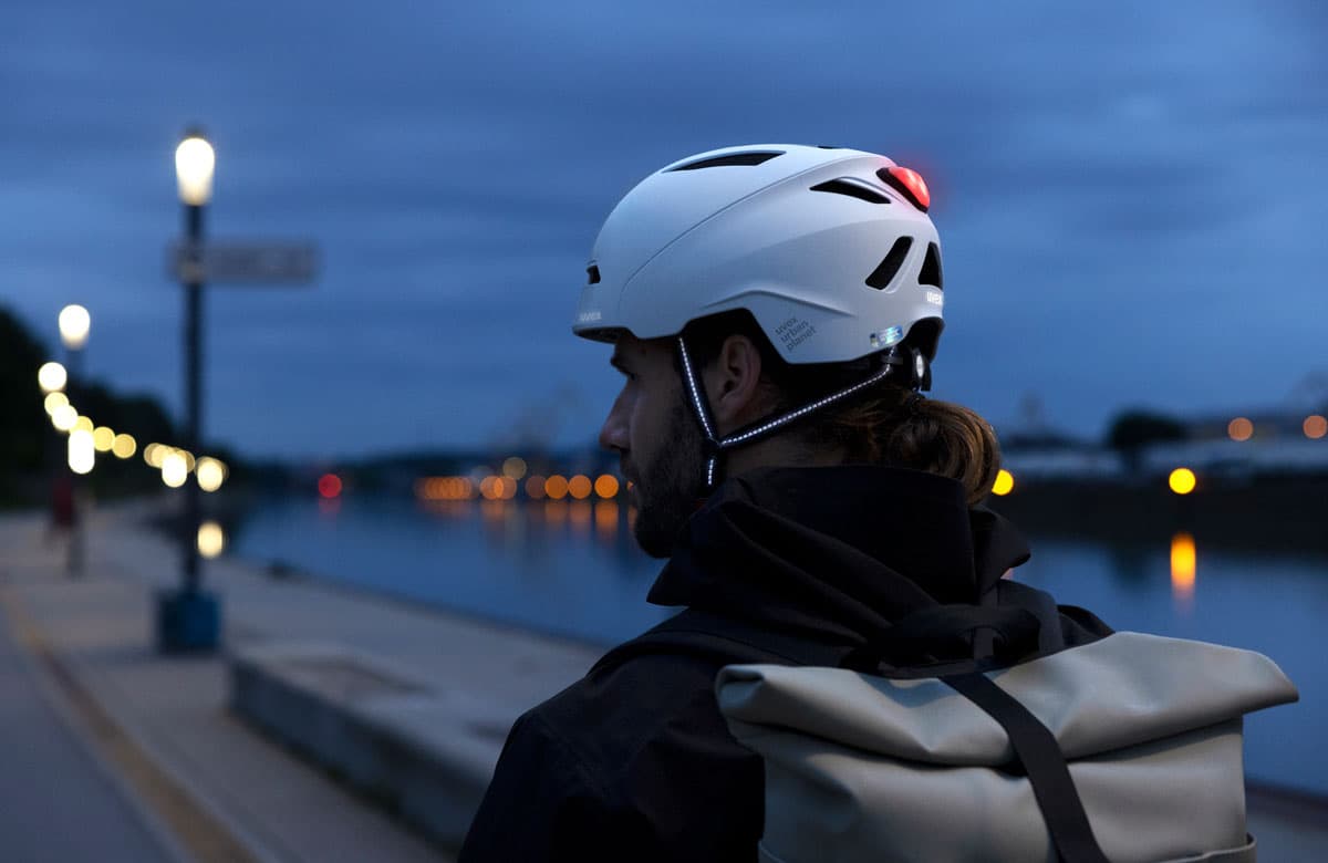 Pyöräilijä hämärässä maisemassa valolla varustettu kypärä päässään. Kuva: Uvex