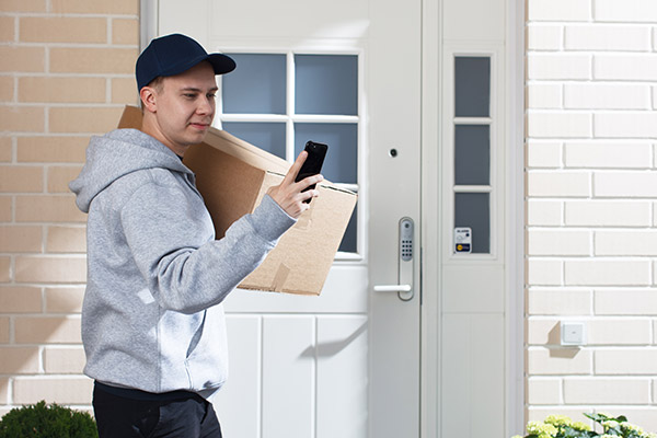 Postinkantaja paketin kanssa ulko-oven edessä