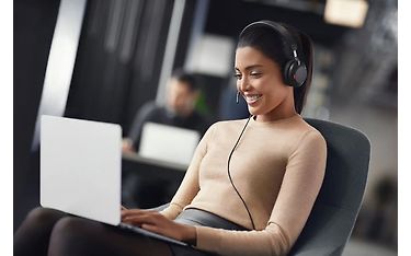 Henkilö työskentelee Jabra Evolve2 40 SE -kuulokkeet päässä kannettavan tietokoneen sylissään.